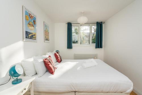 um quarto com uma grande cama branca e uma janela em Super 1BD Garden Flat Islington London em Londres