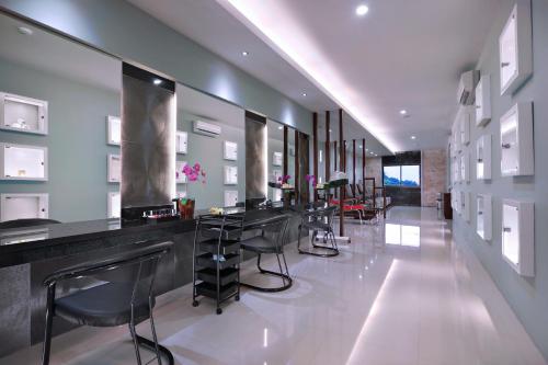 a bar in a room with stools and tables at Famous Hotel Kuta Formerly Permata Kuta Hotel in Kuta