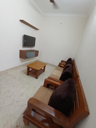 a row of wooden benches in a room with a tv at NISARGA HOMESTAY, Dharmasthala in Dharmastala