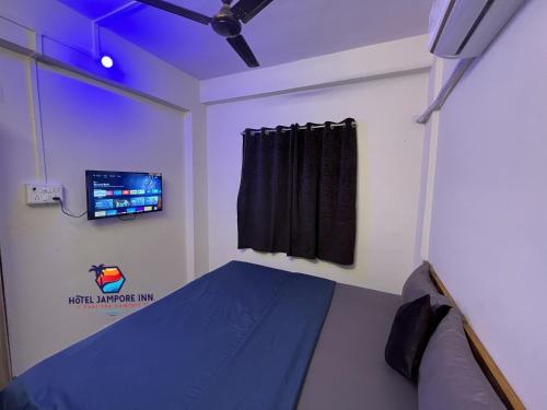 Un dormitorio con una cama y un televisor en la pared. en Hotel Jampore Inn, en Daman