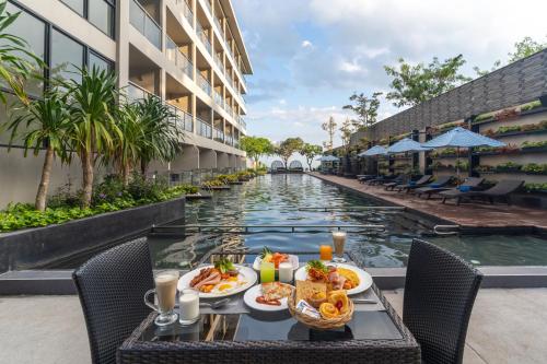 a table with food next to a pool at a hotel at Golden Tulip Pattaya Beach Resort in Pattaya North