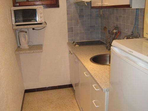 une petite cuisine avec un évier et un micro-ondes dans l'établissement Charmant T3 avec Terrasse et Jardin, Quartier Super Cavalaire, Parking Inclus - FR-1-100-183, à Cavalaire-sur-Mer