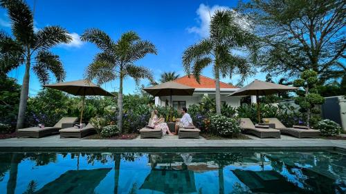 two people sitting on chairs next to a swimming pool at Green Valley Lombok in Selong Belanak