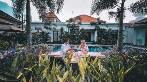 a bride and groom sitting in front of a pool at Green Valley Lombok in Selong Belanak