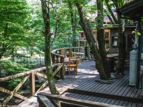 eine Holzterrasse mit Bäumen, einem Tisch und Stühlen in der Unterkunft Glamping Himeshara - Vacation STAY 01948v in Kirishima