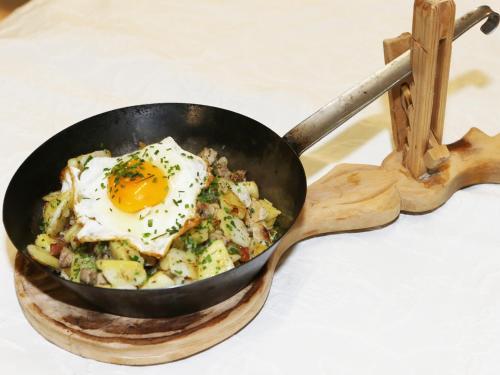 a frying pan with an egg on top of food at Gasthof Pension Madseiterhof in Tux