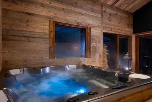 a bath tub with blue water in a wooden bathroom at Hôtel et Spa Le Vermont in Le Grand-Bornand