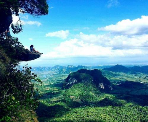 a person sitting on a cliff in the mountains at K-Bunk AoNang Center in Ao Nang Beach