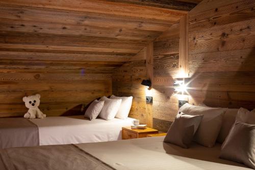 a room with two beds and a teddy bear sitting on top at Hôtel et Spa Le Vermont in Le Grand-Bornand