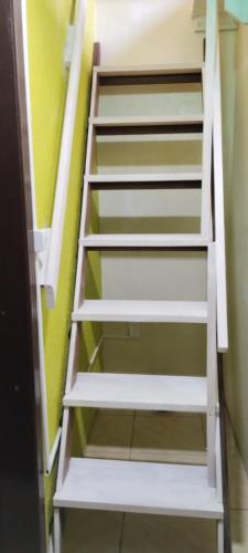 a white staircase in a room with a green wall at Pousada Atlântica stay home in Tramandaí