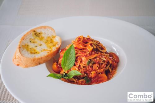a white plate with a bowl of spaghetti and a piece of bread at Combo Beach Hotel Samui in Chaweng