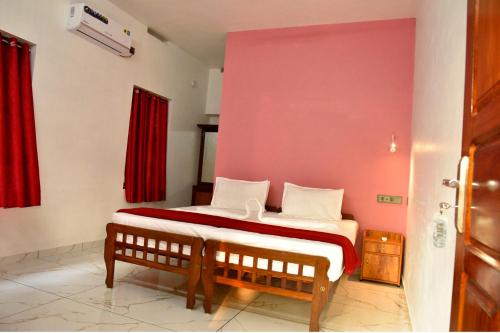 a bedroom with a bed with a red wall at Dhakshina Homestay in Cochin