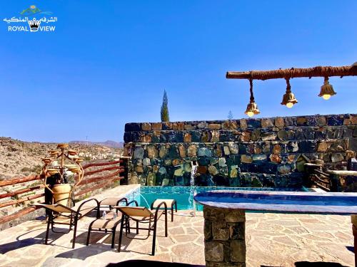 d'une terrasse avec une table et des chaises à côté de la piscine. dans l'établissement Royal view Villa استراحة الشرفة الملكية, à Sayq