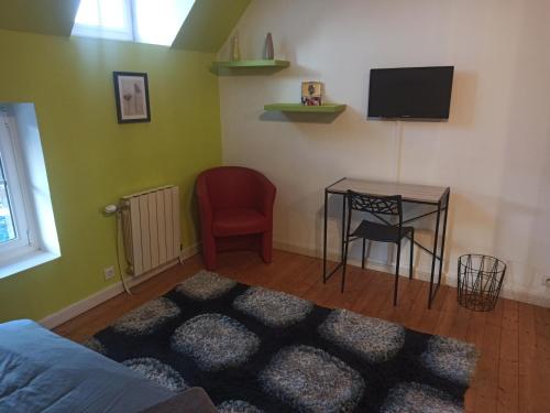 een kamer met een tafel, een tv en een stoel bij Belle Longère in Campeaux