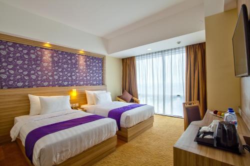 a hotel room with two beds and a tv at Hotel Horison Ultima Bekasi in Bekasi