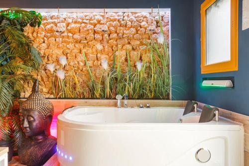 a bathroom with a bath tub with a painting on the wall at JADE Hammam & Jacuzzi in Brie-Comte-Robert