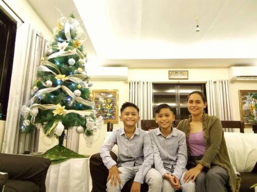 três pessoas sentadas num sofá em frente a uma árvore de Natal em Bohol Sweet Home em Guindulman