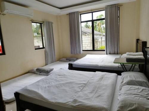 um quarto com 3 camas e uma janela em Bohol Sweet Home em Guindulman