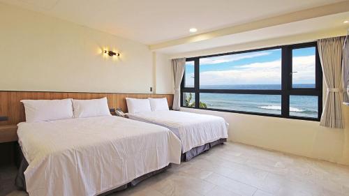 two beds in a room with a view of the ocean at Smile Ocean Homestay in Green Island