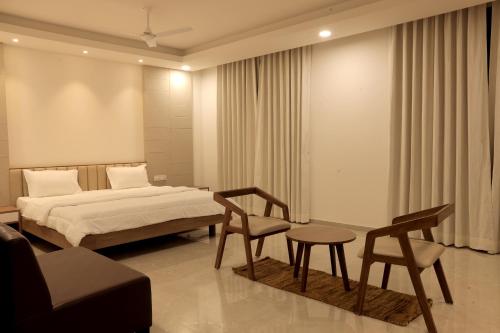 a bedroom with a bed and two chairs and a couch at The Presidential Suites in Bhuj
