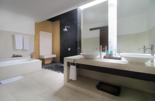 a bathroom with two sinks and a bath tub and a tubermott at Sagara Villas and Suites Sanur by AHM in Sanur