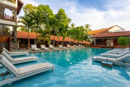 Bauhinia Resort & Spa Phu Quoc في فو كووك: مسبح في منتجع مع كراسي جلوس واشجار