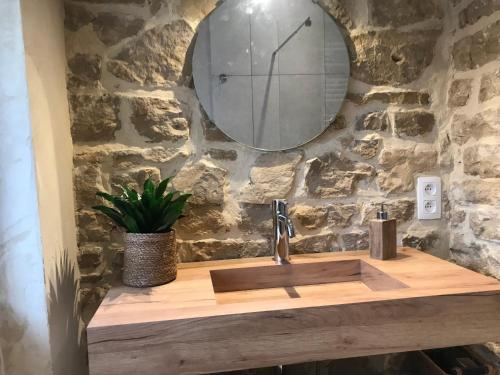 a bathroom sink with a mirror on a stone wall at La Maison Blanche de Martué in Florenville