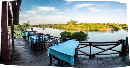 Ban Khon的住宿－Chanhthida Riverside Guesthouse and The River Front Restaurant，河边的甲板上摆放着桌椅