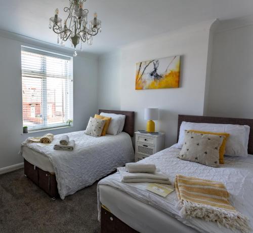 - une chambre avec 2 lits et un lustre dans l'établissement Wavecrest Cottage - Characterful 3 Bedroom Holiday Cottage, à Flamborough