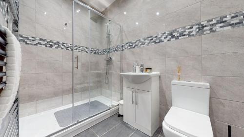 a bathroom with a shower and a toilet and a sink at JDB Romford 5-Bedroom House with parking in Goodmayes