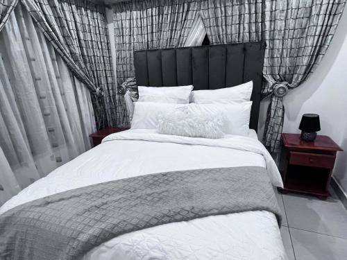 a bedroom with a large white bed with a black headboard at Beevap Guesthouse in Pretoria