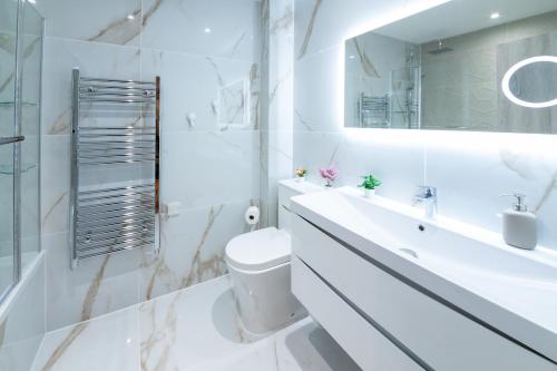 La salle de bains blanche est pourvue de toilettes et d'un lavabo. dans l'établissement LUX 2 Bedrooms - 2 Bathrooms - F7, à Londres