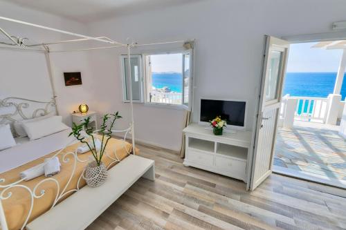 a white room with a bed and a television at With-inn Mykonos Suites in Tourlos