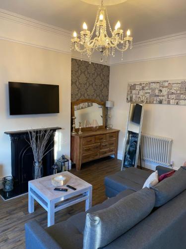 a living room with a couch and a chandelier at The Fort Lytham St Annes in Lytham St Annes