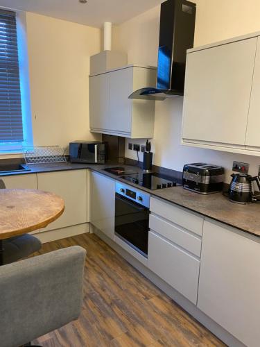 a kitchen with white cabinets and a table and a counter top at The Fort Lytham St Annes in Lytham St Annes