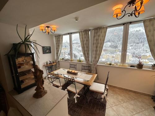 a living room with a table and chairs and windows at Panorama & SPA Apartment Kaiser Franz Josef I im Schillerhof in Bad Gastein