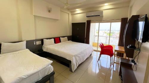 a hotel room with two beds and a television at The Gir Harmony Hotel in Sasan Gir