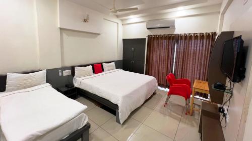 a hotel room with two beds and a television at The Gir Harmony Hotel in Sasan Gir
