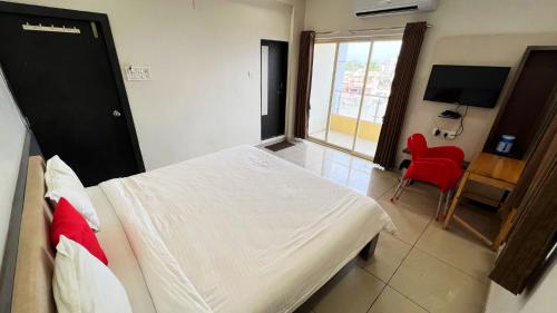 a bedroom with a bed and a tv and a red chair at The Gir Harmony Hotel in Sasan Gir