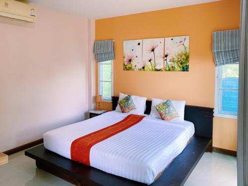 a bedroom with a large white bed with orange walls at i-Style Lanta Boutique House --- SHA Extra Plus in Ko Lanta