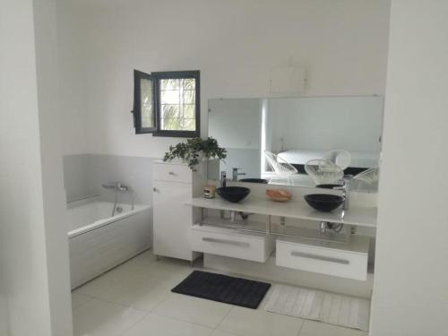 a white kitchen with a sink and a tub at Villa Carabane in Somone