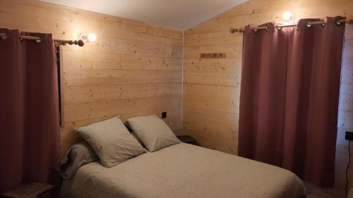 une chambre avec un lit dans une pièce aux murs en bois dans l'établissement La tanière du lac d Aiguebelette, à Lépin-le-Lac