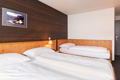 two twin beds in a room with wooden walls at Jungfrau Lodge, Annex Crystal in Grindelwald