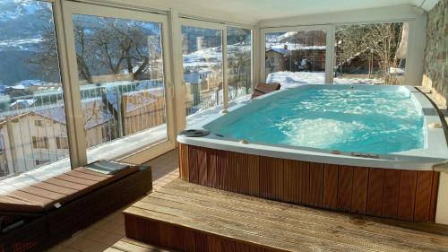 a large jacuzzi tub in a room with windows at Villetta Glicine in Brentonico