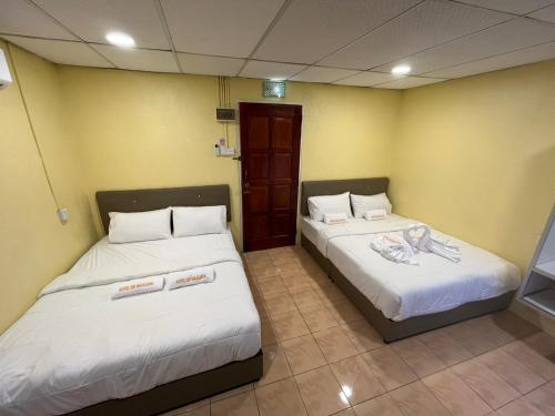 2 camas en una habitación con paredes amarillas en Hotel Sri Maju Jaya, en Kota Bharu