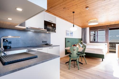 a kitchen with white cabinets and a dining room with a bed at Hapimag Ferienwohnungen St Michael in Sankt Michael im Lungau