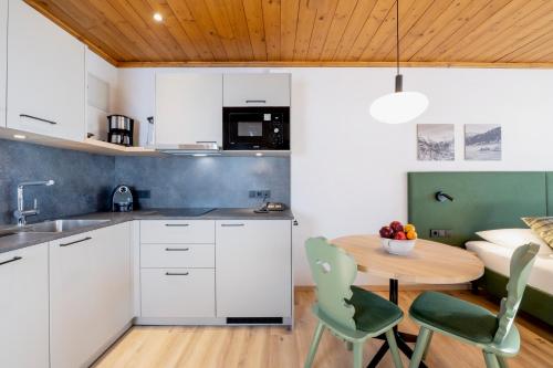 a kitchen with white cabinets and a table and chairs at Hapimag Ferienwohnungen St Michael in Sankt Michael im Lungau