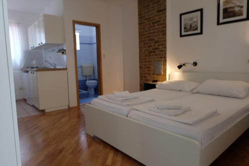 Cama blanca en habitación con cocina en Apartments Golubic en Pula