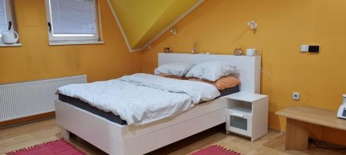 a white bed in a room with yellow walls at Hiša pri Bici in Slovenj Gradec