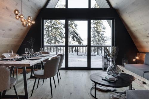 een eetkamer met een tafel, stoelen en ramen bij LUXE VISTA Mountain Chalet Cermis - direkt an der Skipiste und Alm in Cavalese